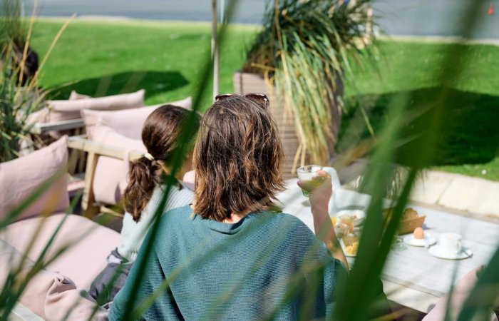 Eine Frau frühstückt mit ihrer Tochter auf der Seeterrasse im Haus am Meer auf Norderney.